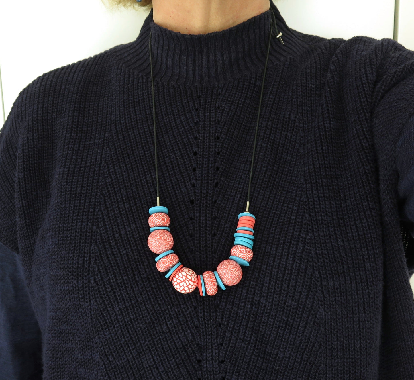 Person wearing a black sweater with a colorful beaded necklace